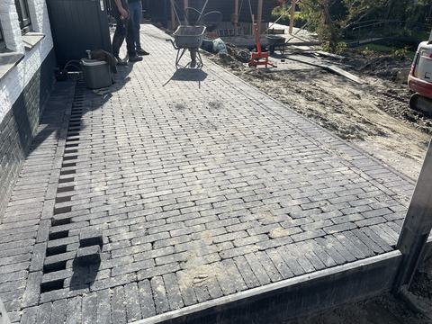 Terras van gebakken klinkers met afwateringsgoot langs de gevel