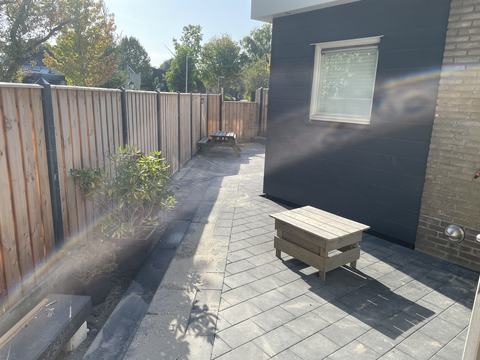 Terras van grijze klinkers langs een uitbouw